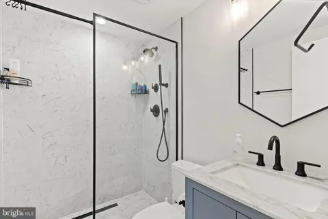 a bathroom with a granite countertop shower sink vanity and toilet