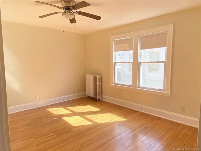 a view of an empty room with a window and wooden floor
