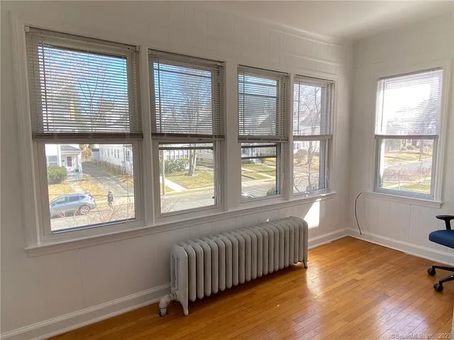 a view of an empty room with wooden floor and a window