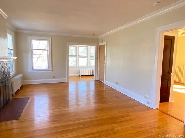 an empty room with wooden floor and windows with curtains
