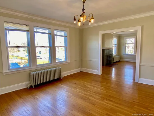 a view of an empty room with window and wooden floor