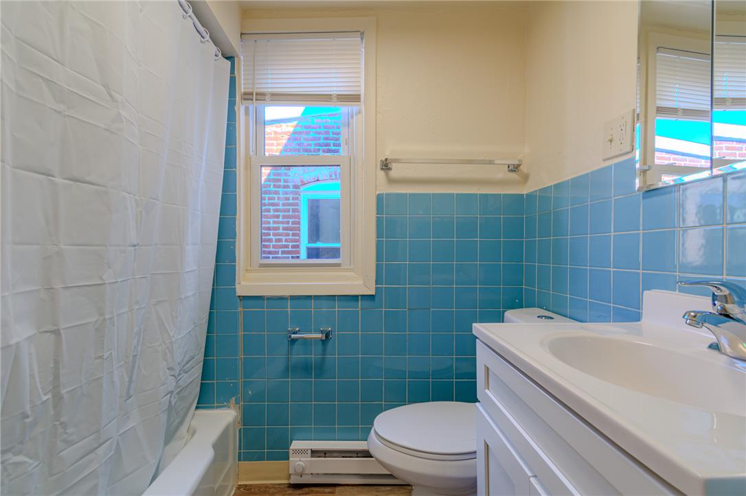 820 North 5th Street Allentown, PA 18102 - Photo 27 of 39 A compact full bathroom featuring vibrant blue tiled walls, a white tub with shower, and a clean vanity with sink.
