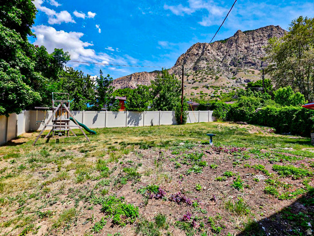 1272 Cook Street Ogden, UT 84404 - Photo 56 of 58 Expansive backyard featuring a partial privacy fence, mature perimeter greenery, and a prominent mountain backdrop