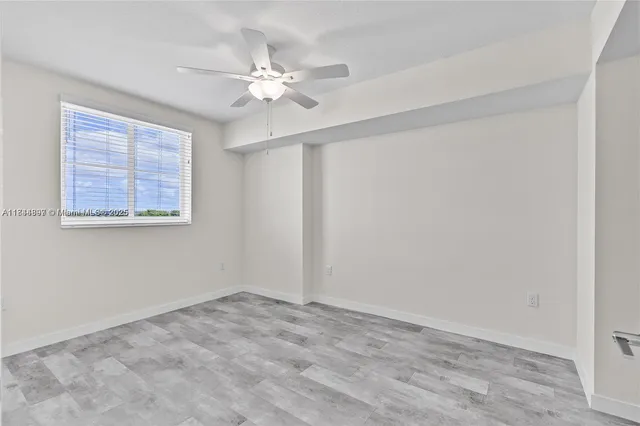 a view of an empty room with chandelier fan
