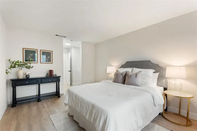 a bedroom with a bed and a potted plant on the dresser