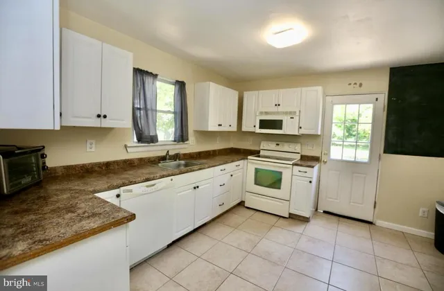 a kitchen with granite countertop white cabinets and white appliances