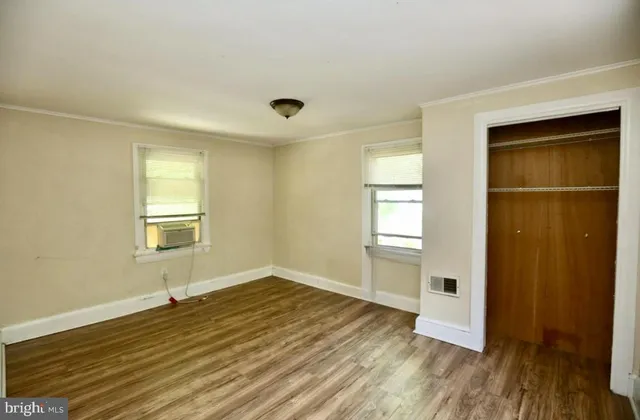 an empty room with wooden floor and windows