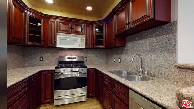 a kitchen with granite countertop stainless steel appliances a stove sink and cabinets
