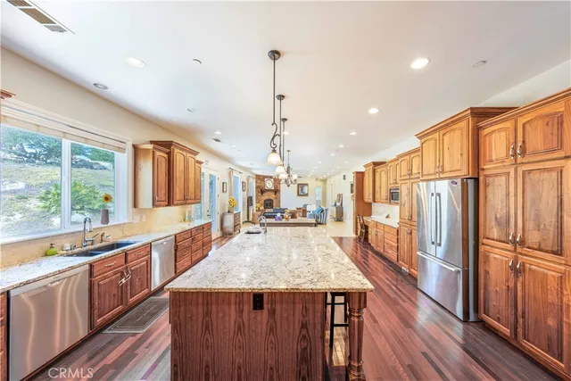 a kitchen with stainless steel appliances granite countertop a refrigerator a sink dishwasher a stove and white countertops with wooden floor