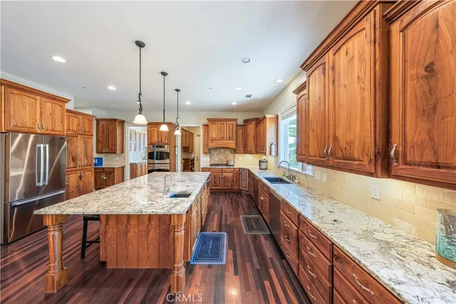 a kitchen with stainless steel appliances granite countertop wooden floor window and wooden cabinets