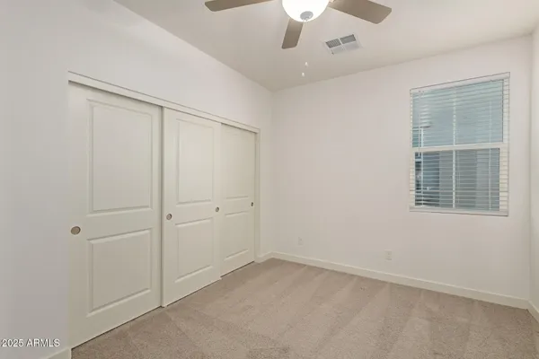 an empty room with a ceiling fan and a window