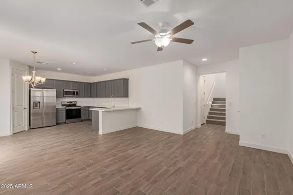a view of a livingroom with kitchen appliances and a ceiling fan