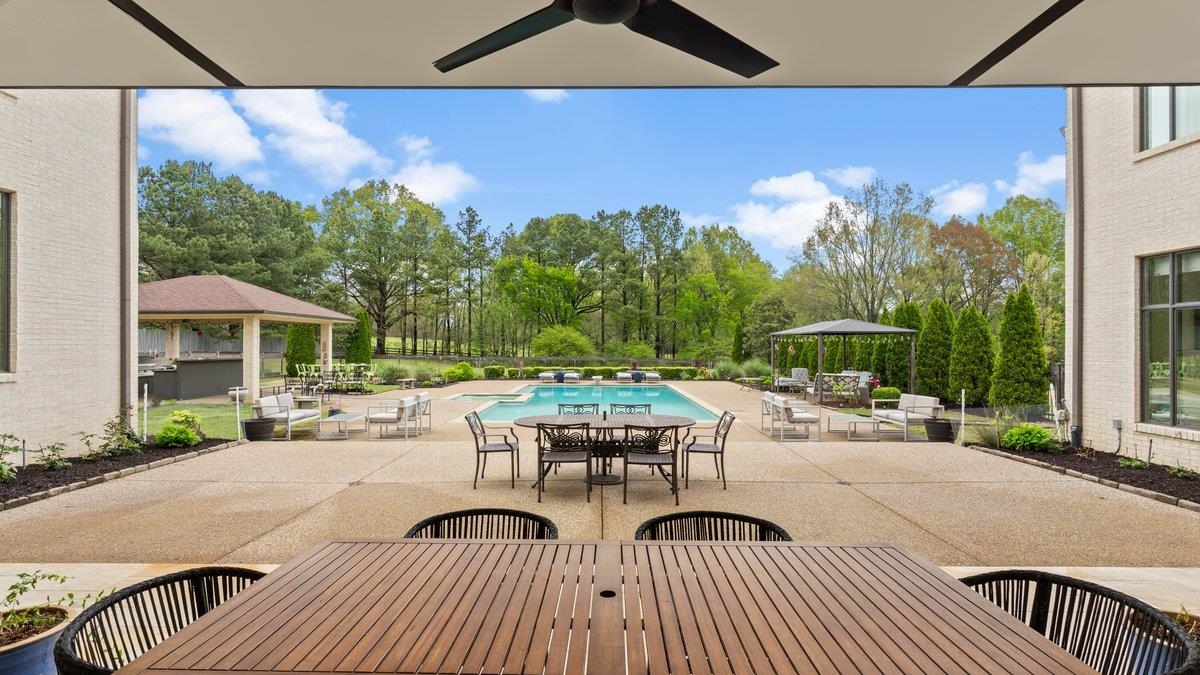 9942 Legends Drive Collierville, TN 38139 - Photo 7 of 40 a view of a patio with couches table and chairs under an umbrella with wooden floor