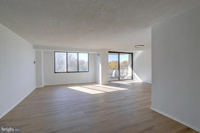 a view of an empty room with wooden floor and window
