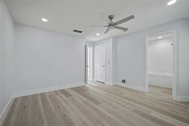 an empty room with wooden floor fan and windows