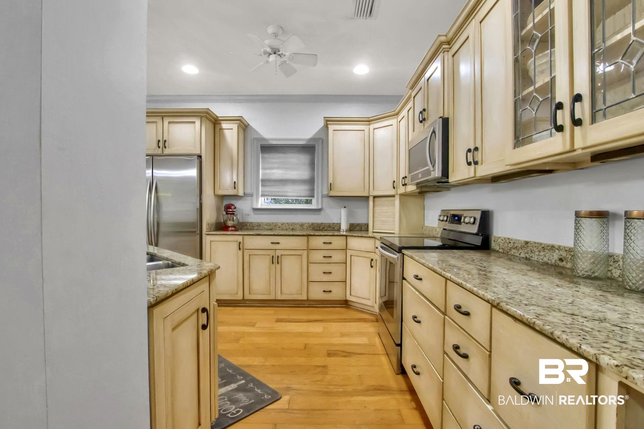 9002 Parliament Circle Daphne, AL 36526 - Photo 24 of 73 Kitchen featuring light brown cabinetry, appliances with stainless steel finishes, ceiling fan, light stone counters, and light wood flooring, wine refrigerator.