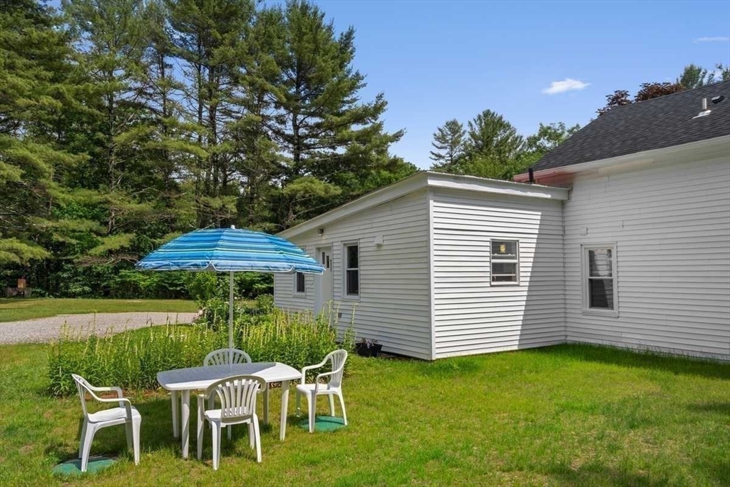 166 Packardville Road Pelham, MA 01002 - Photo 32 of 34 a view of a white house with a yard and lawn chairs under an umbrella