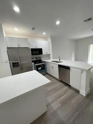 a large kitchen with stainless steel appliances a sink dishwasher stove top oven and cabinets