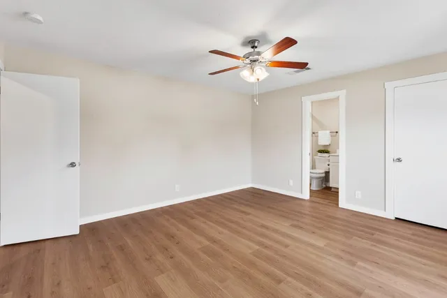an empty room with wooden floor closet and fan
