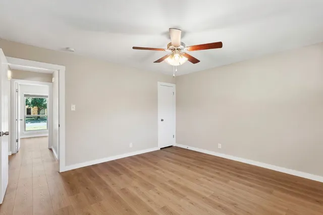 an empty room with wooden floor and fan