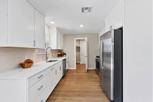 a kitchen with stainless steel appliances a refrigerator sink and white cabinets