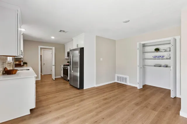a view of a kitchen with refrigerator and wooden floor