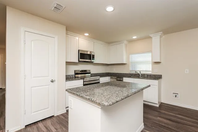 a kitchen with granite countertop a sink stove and refrigerator