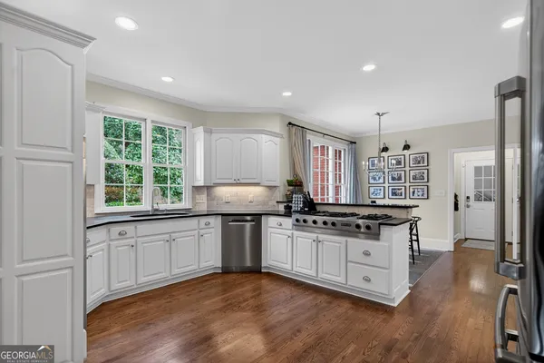 a kitchen with granite countertop white cabinets stainless steel appliances and a window