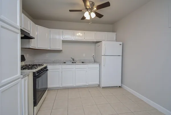 a kitchen with cabinets appliances and a ceiling fan