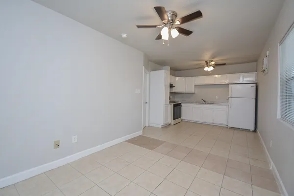 an empty room with chandelier fan and closet area