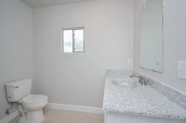 a bathroom with a granite countertop sink and a toilet