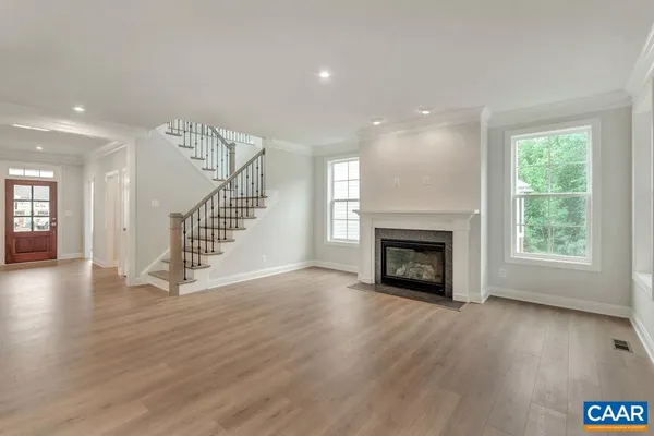 an empty room with wooden floor fireplace and windows