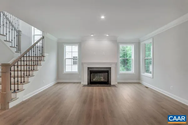 an empty room with wooden floor fireplace and windows