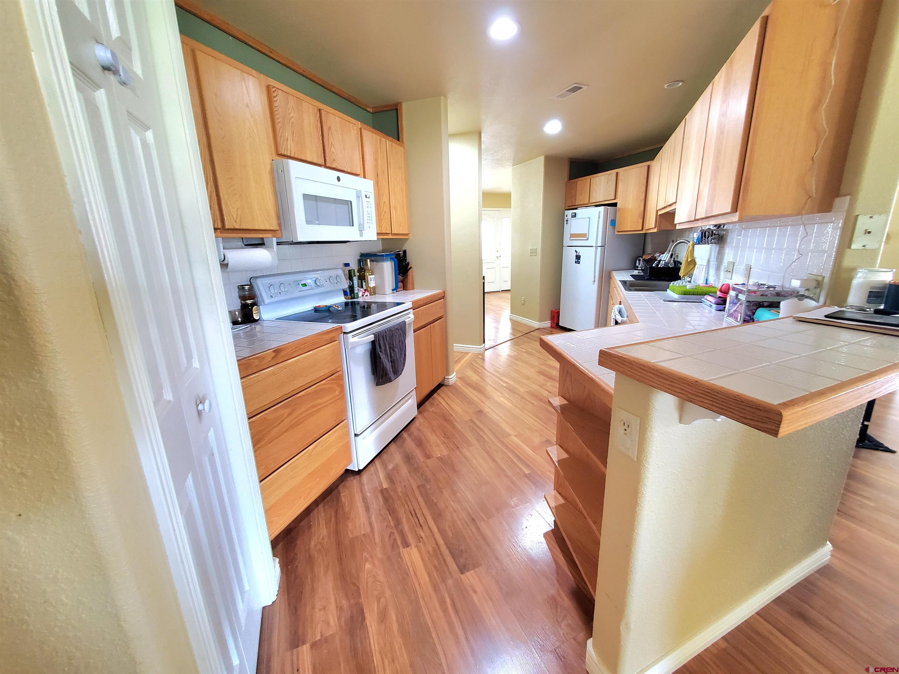 7095 Buena Vista Road Delta, CO 81416 - Photo 11 of 33 a kitchen with stainless steel appliances granite countertop a refrigerator a sink dishwasher a stove and white countertops with wooden floor