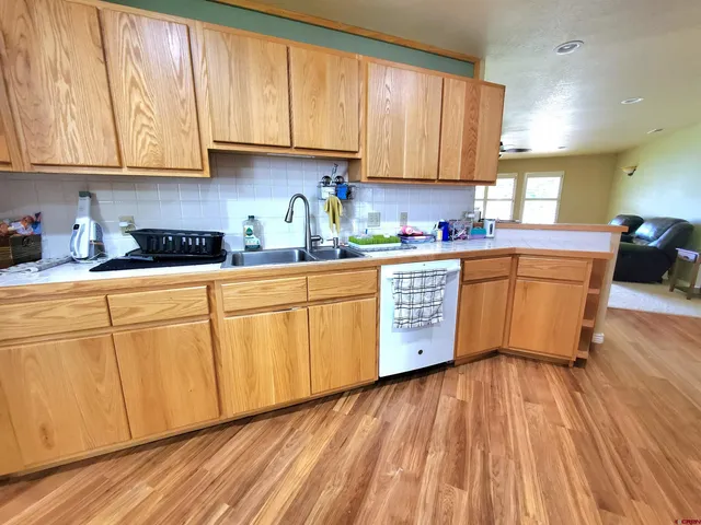 a kitchen with stainless steel appliances granite countertop wooden cabinets a sink and dishwasher with wooden floor
