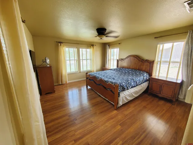 a spacious bedroom with a bed and wooden floor