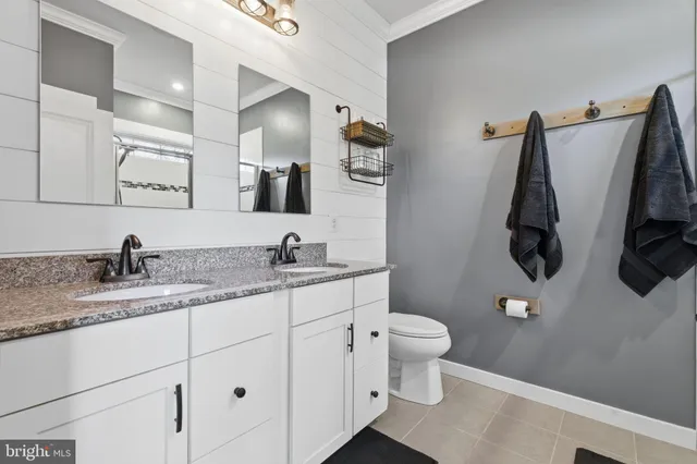 a bathroom with a granite countertop sink and a toilet