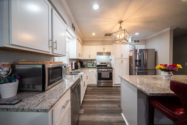 a kitchen with granite countertop kitchen island stainless steel appliances a refrigerator sink stove microwave and cabinets