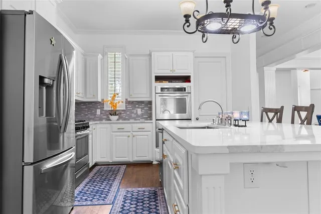 a kitchen with stainless steel appliances granite countertop a sink a stove a refrigerator cabinets and chairs