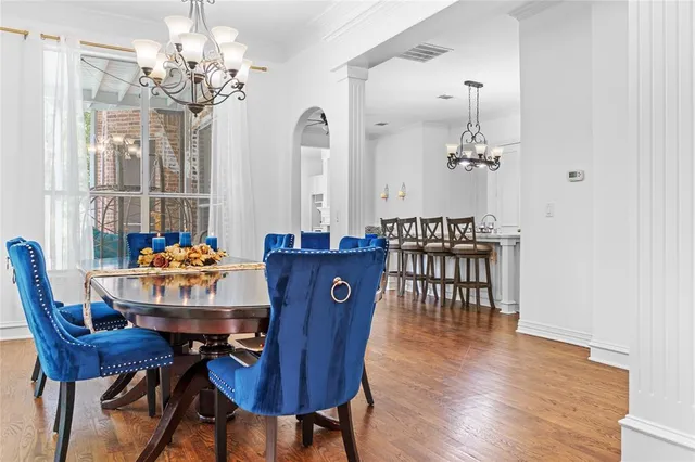 a dining room with furniture a chandelier and wooden floor