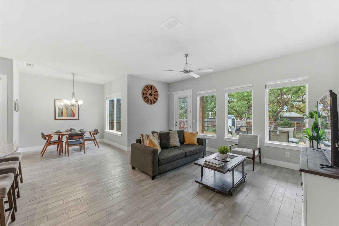 Living area featuring light wood-style flooring, a ceiling fan, and a chandelier