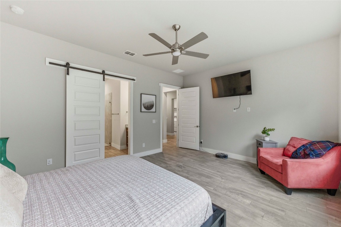 184 Granite Road Spring Branch, TX 78070 - Photo 12 of 27 Bedroom with a barn door, ceiling fan, light wood finished floors, and ensuite bathroom