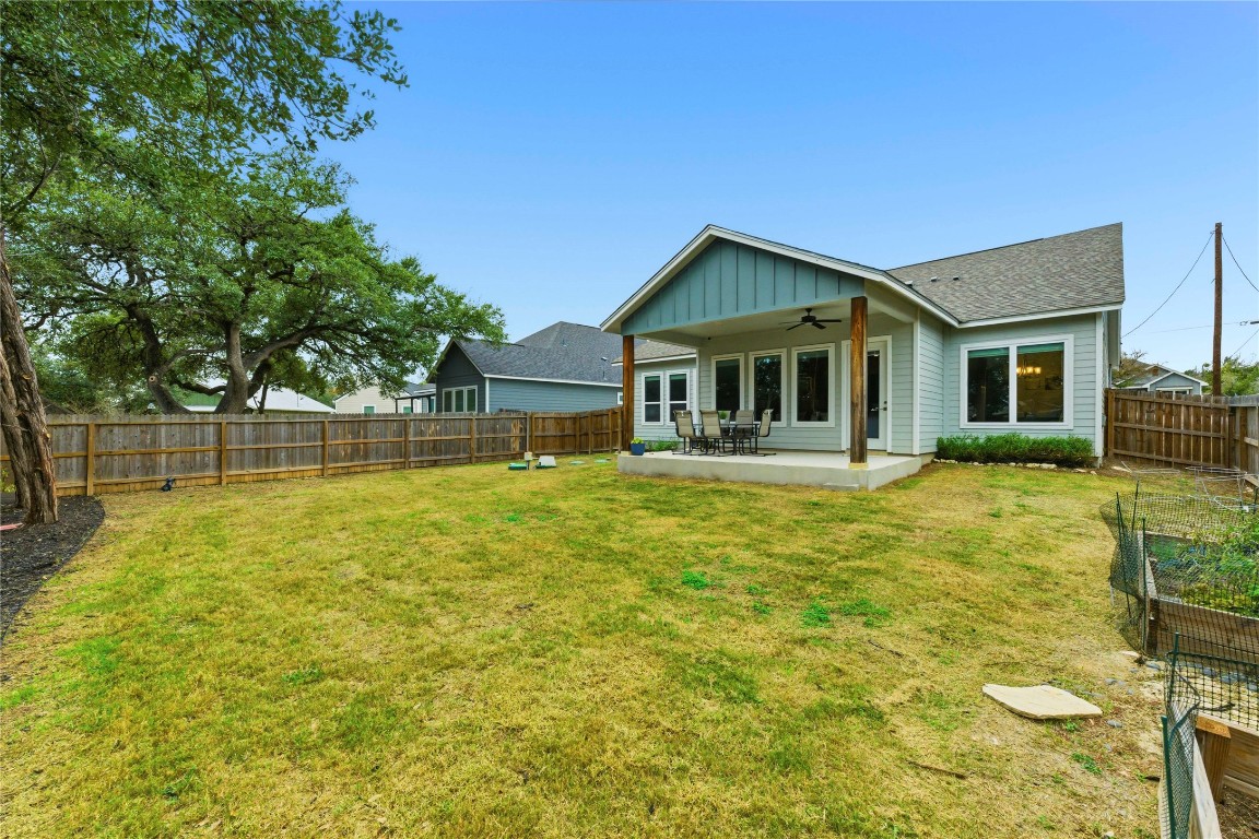 184 Granite Road Spring Branch, TX 78070 - Photo 24 of 27 Back of house with board and batten siding, ceiling fan, a patio area, a fenced backyard, and a shingled roof