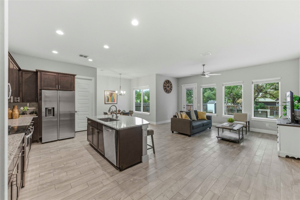 184 Granite Road Spring Branch, TX 78070 - Photo 6 of 27 Kitchen featuring dark brown cabinetry, stainless steel appliances, light stone counters, decorative light fixtures, and an island with sink
