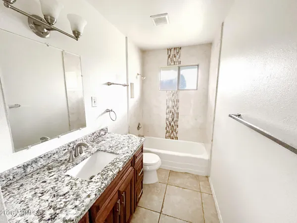 a bathroom with a granite countertop sink a toilet and shower