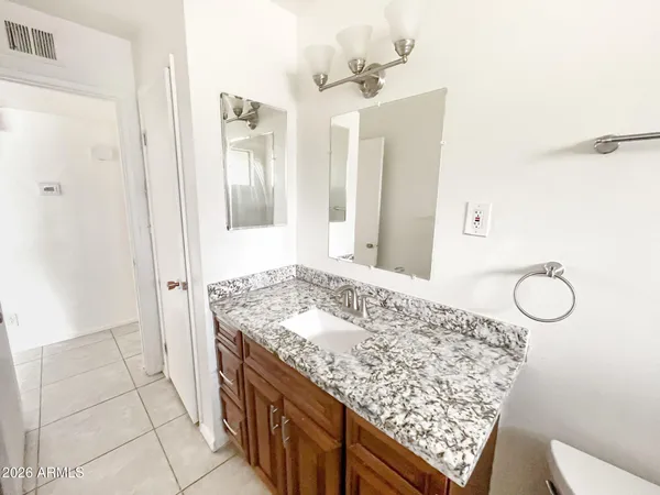 a bathroom with a granite countertop sink a mirror and shower