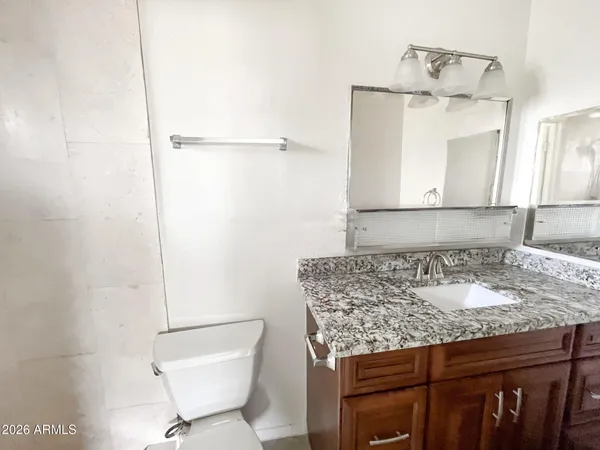 a bathroom with a granite countertop sink and a toilet