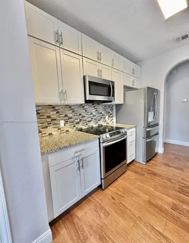 a large white kitchen with granite countertop a sink