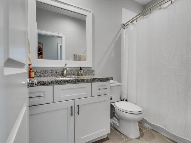 a bathroom with a granite countertop sink vanity mirror and toilet