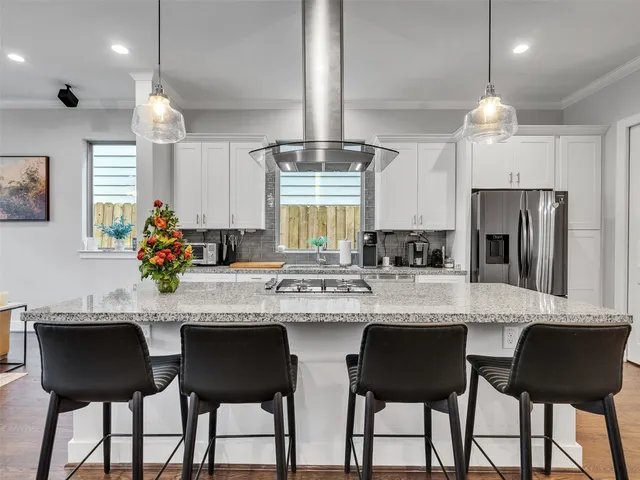 a kitchen with stainless steel appliances granite countertop white cabinets a dining table and chairs